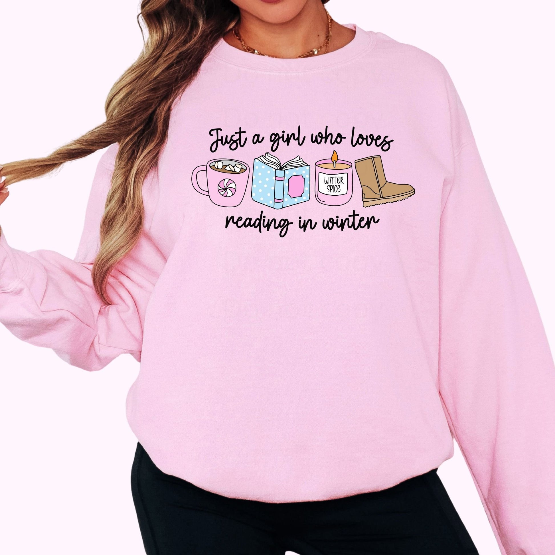 Person wearing a pink sweatshirt with a graphic and text. Just a girl who loves reading in winter.