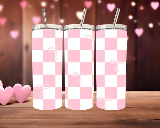 Three pink and white checkered tumblers with bow designs on a wooden surface.